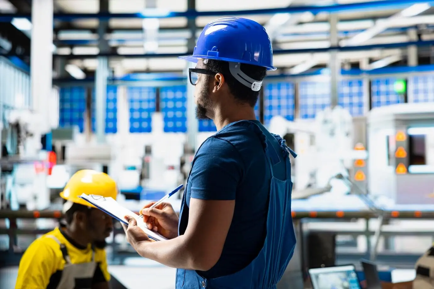Afroamerikanische Aufsichtsperson bewertet Kennzahlen für erneuerbare Energien in einer Fabrik.